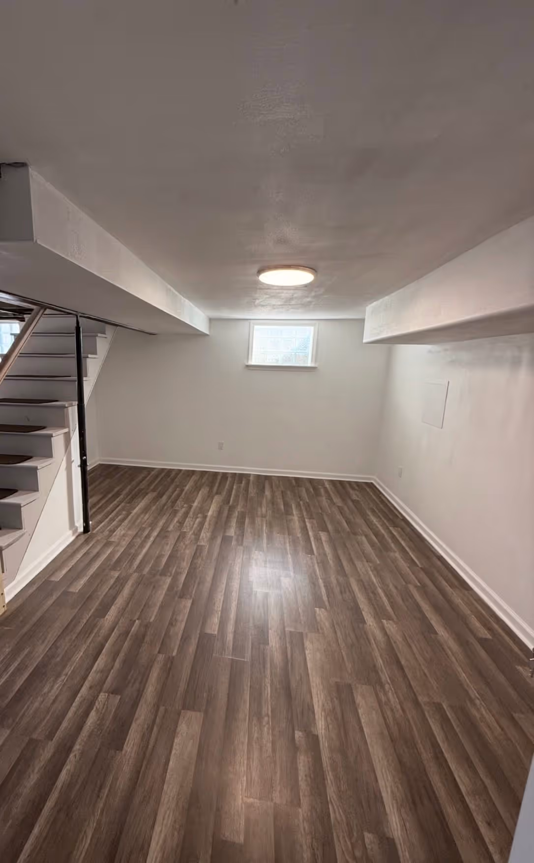 Finished basement with light walls and wood-look flooring