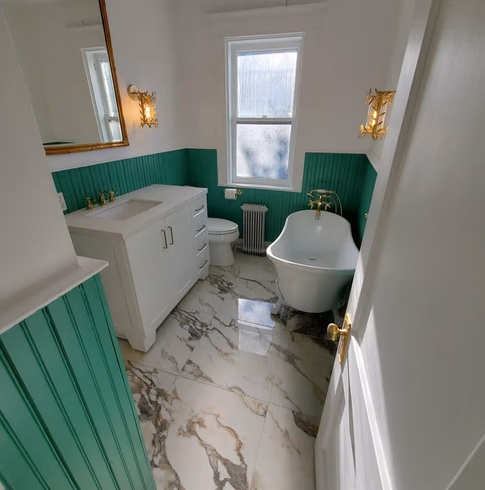 Finished bathroom with a clawfoot tub, green wall paneling, and a white vanity