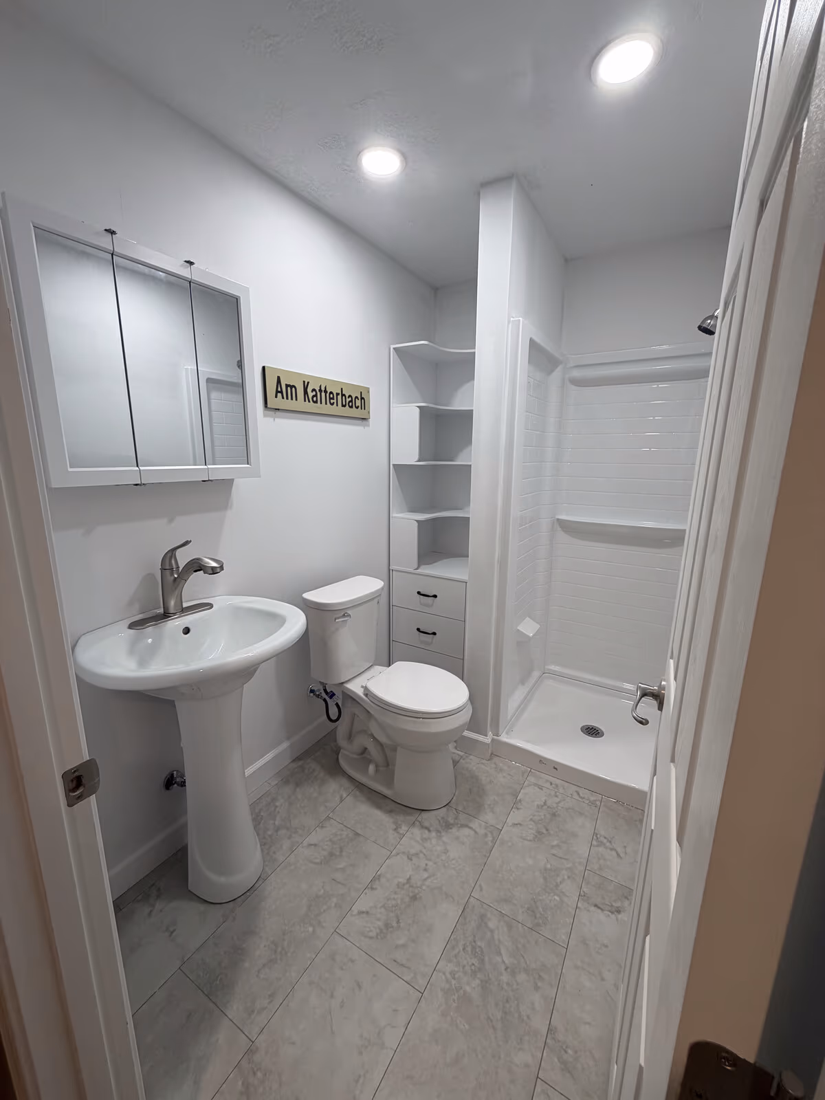 Finished basement bathroom with a walk-in shower, pedestal sink, and tile floor