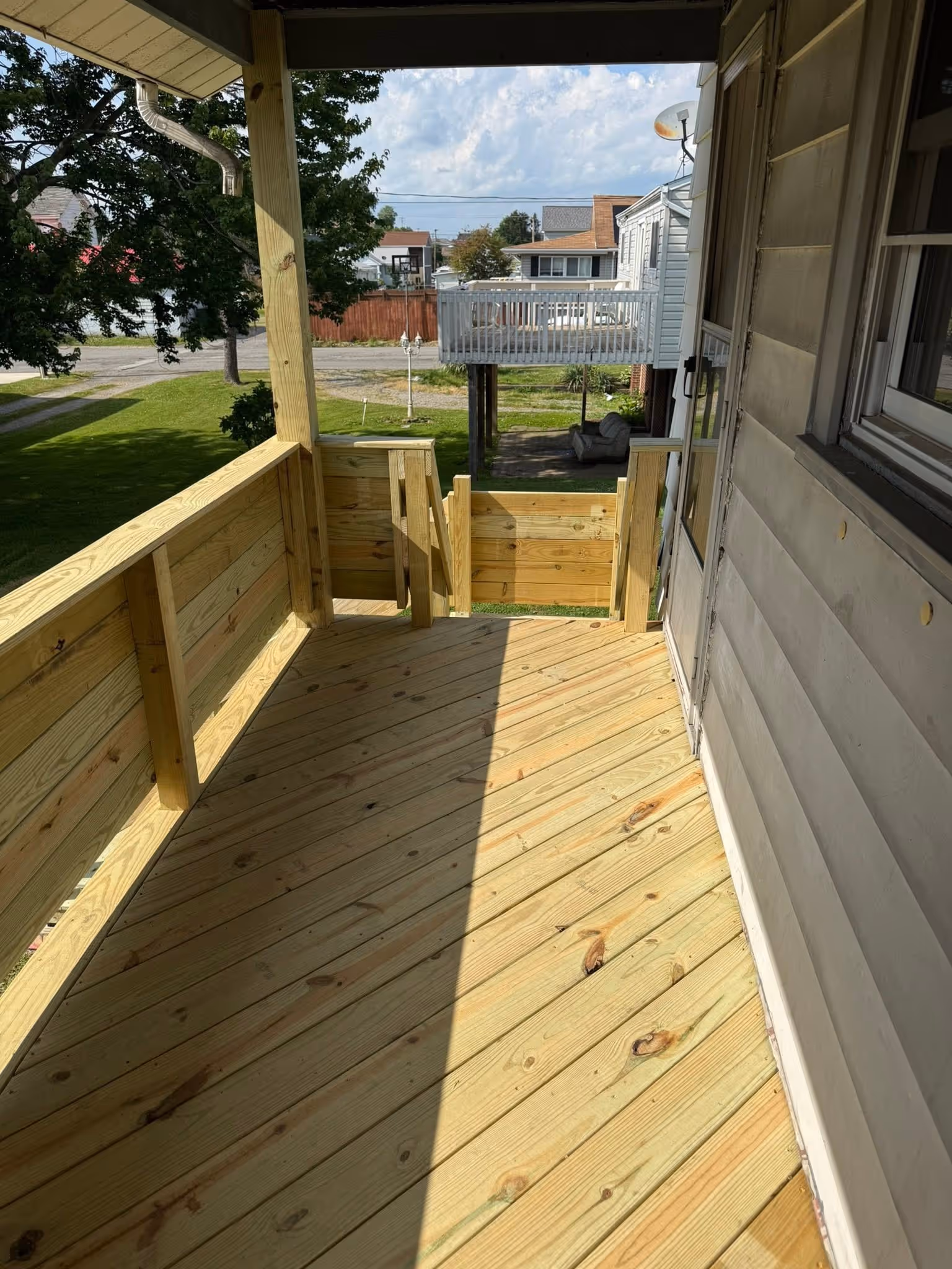 Wood porch floor and railing viewed along the side of a house