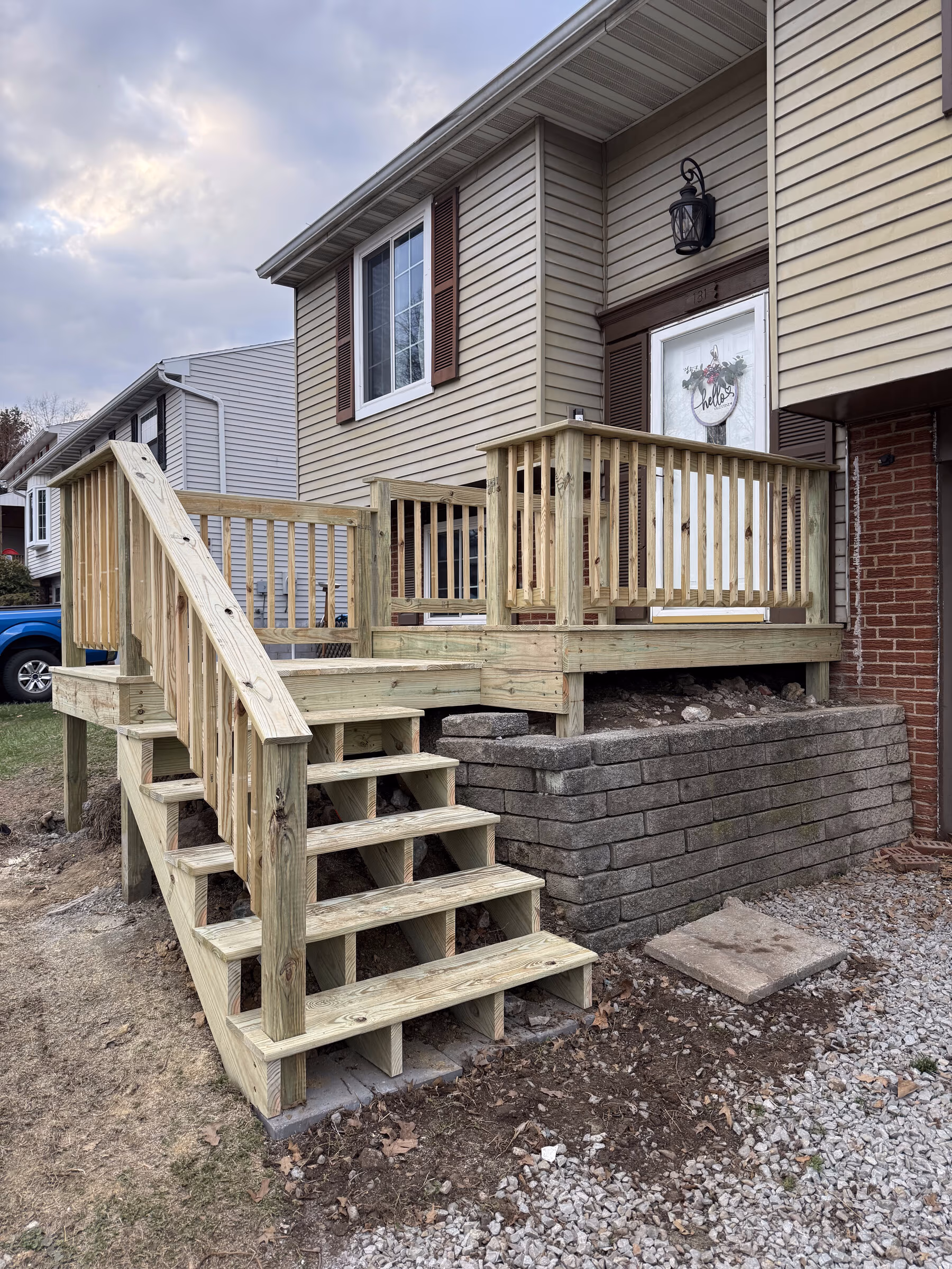 New pressure-treated wood front entry deck with stairs and railings