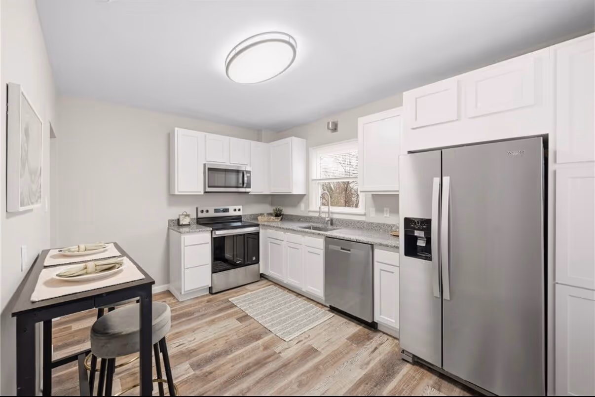 Finished kitchen remodel from the dining side, with white cabinets and stainless appliances