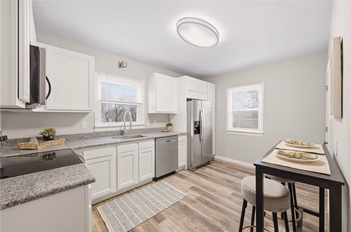 Finished kitchen remodel with white cabinets, granite counters, and stainless appliances